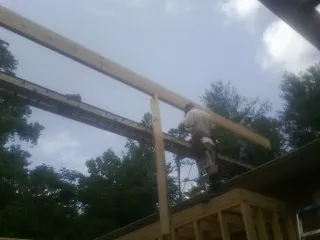 Carpenter setting a ridge beam over a new addition frame — Ice Dam Removal by Roofing Brothers in Phelps