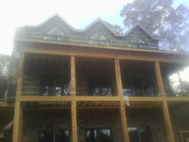 Dormers and porch framing on a large log home under construction — Roof Coating work by our crew in Phelps