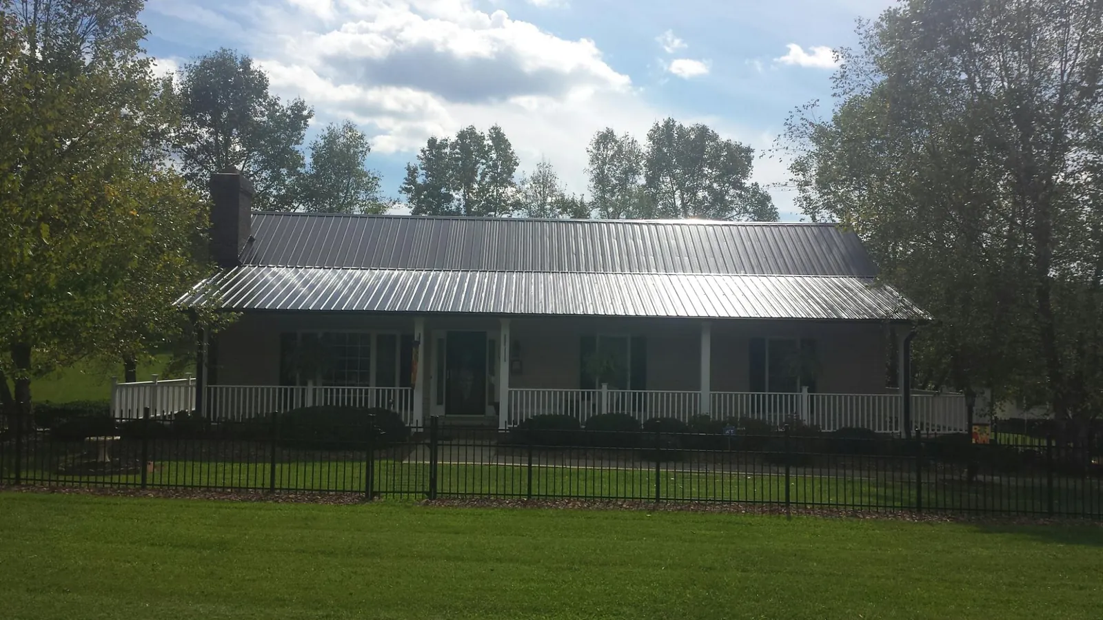 Gray metal roof on a brick ranch with a full width front porch — Gutter Guard Installation work by our crew in Phelps