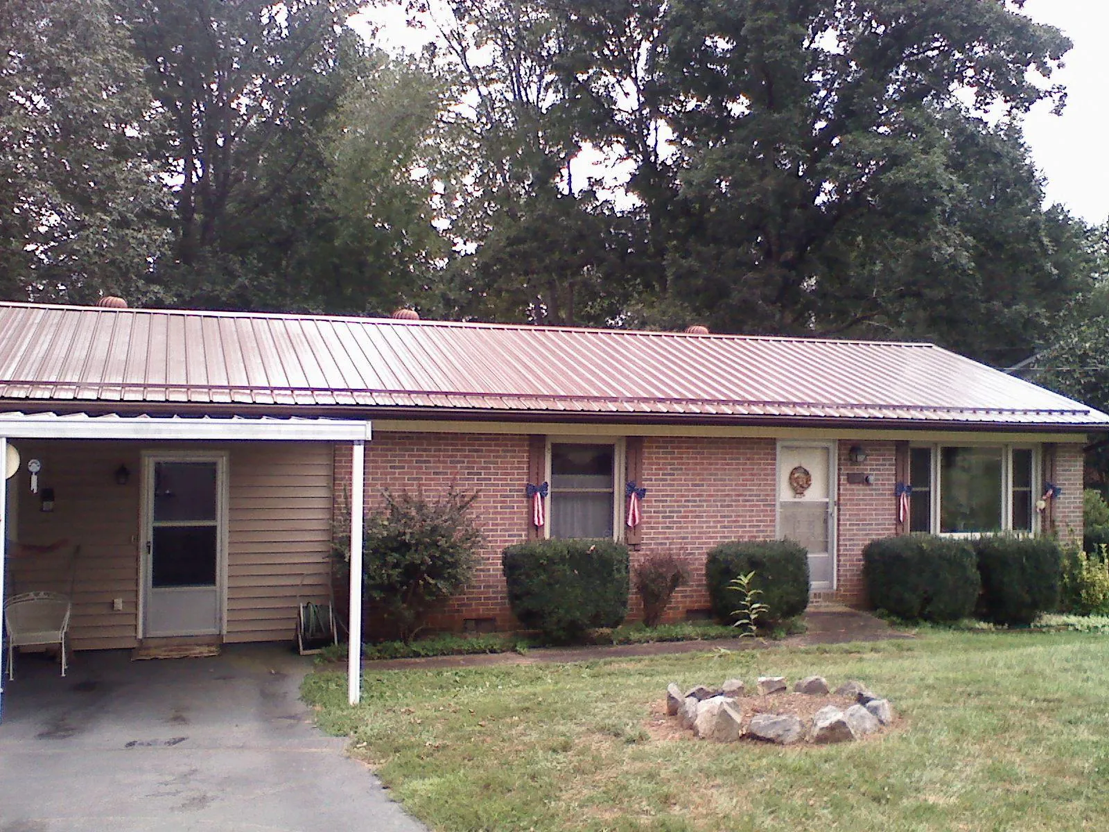 Bronze metal roof and carport on a brick ranch home — Roof Repair work by our crew in Phelps